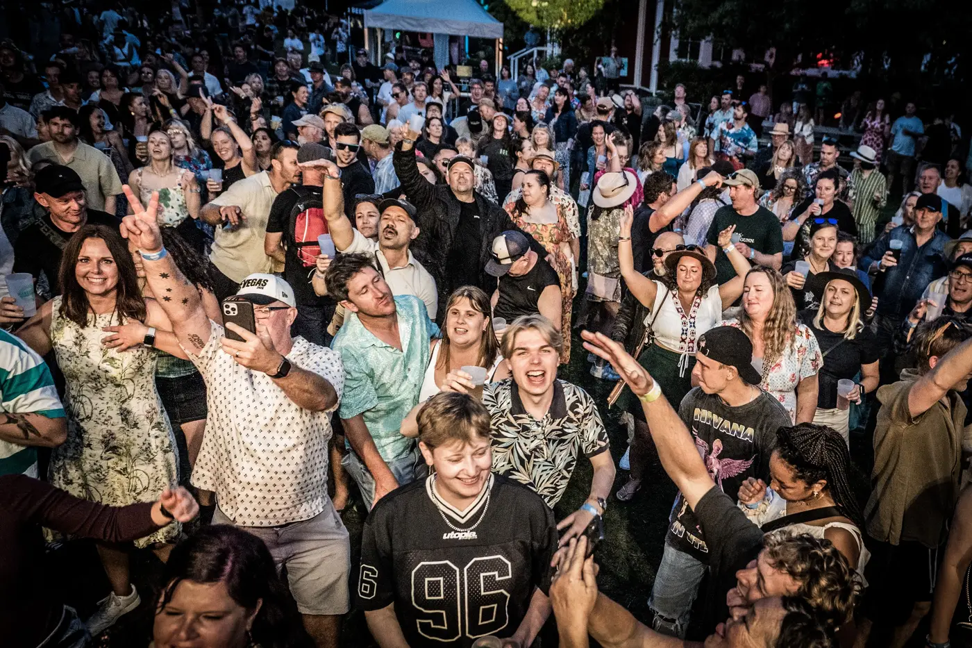 A Danger80s crowd at a live show — packed dance floor under neon stage lighting