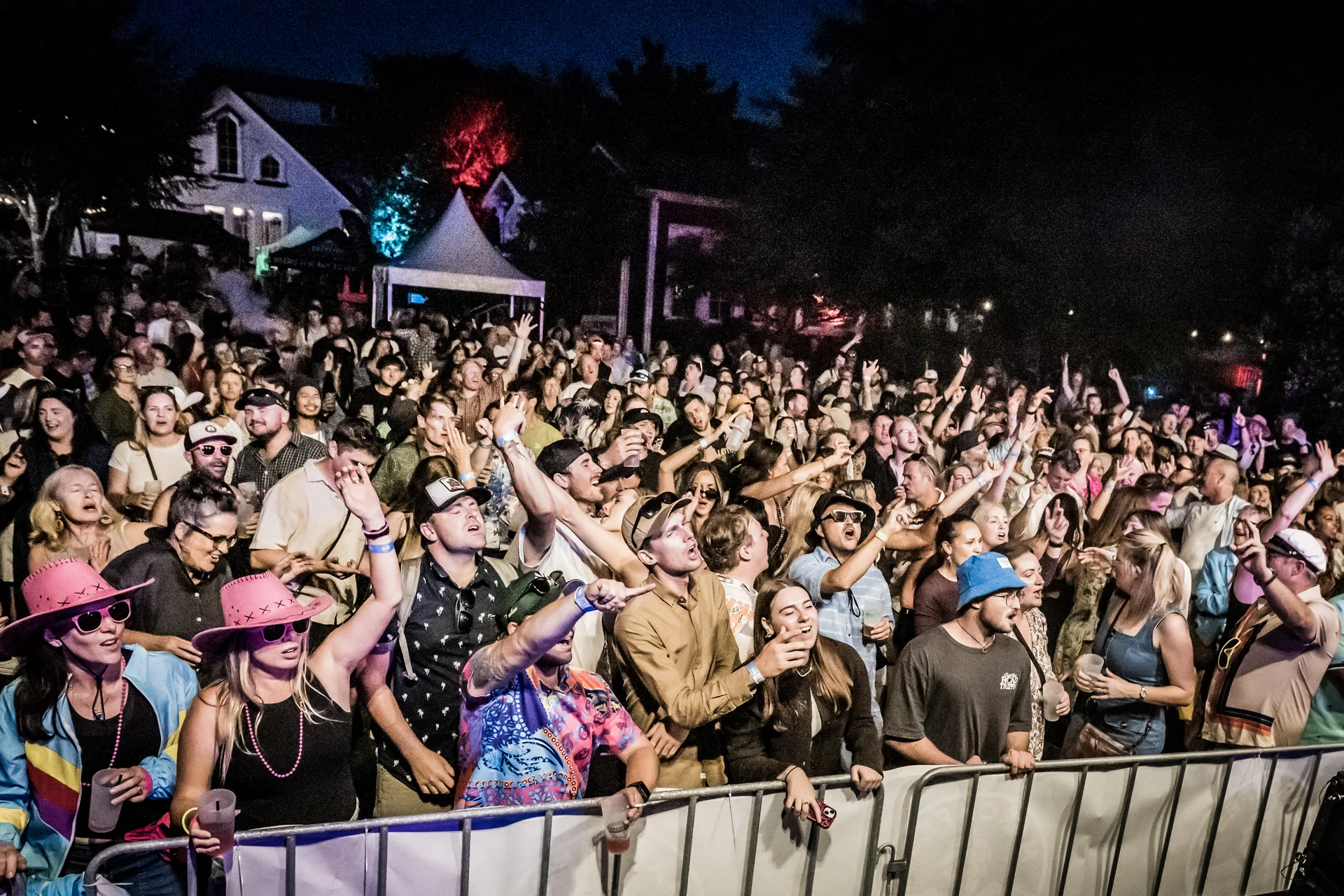 A Danger80s crowd at a live show — packed dance floor under neon stage lighting
