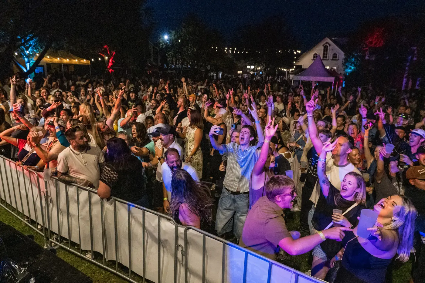 A Danger80s crowd at a live show — packed dance floor under neon stage lighting