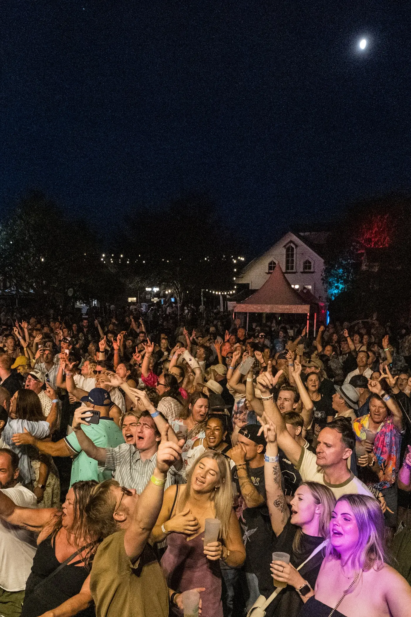 A Danger80s crowd at a live show — packed dance floor under neon stage lighting
