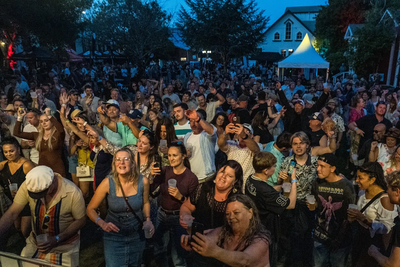 A Danger80s crowd at a live show — packed dance floor under neon stage lighting